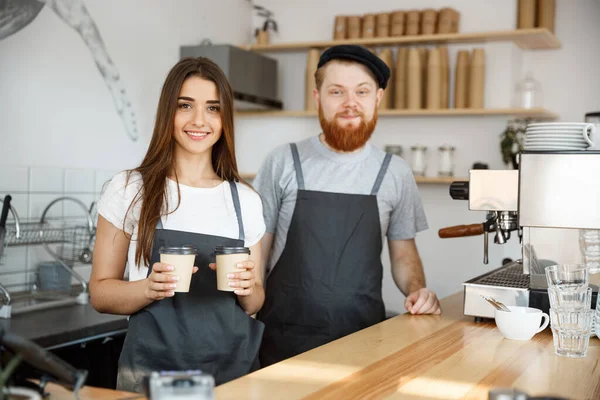 Coffee Business Concept - Positivo jovem barbudo homem e bela atraente senhora barista casal dando tirar xícara de café para custome no café moderno — Fotografia de Stock