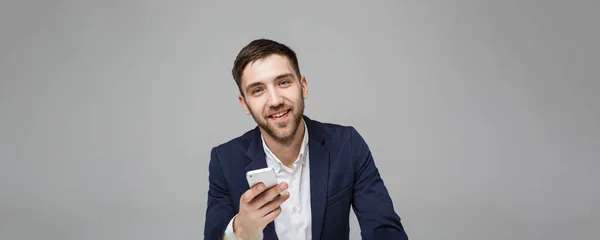 Geschäftskonzept - Porträt gut aussehender, gut aussehender Geschäftsmann im Anzug, der Mobiltelefon spielt und im Büro mit Laptop lächelt. weißer Hintergrund. — Stockfoto