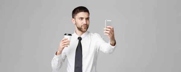 Életmód és üzleti koncepció - portré egy jóképű üzletember tetszik, hogy a selfie vesz el csésze kávét. Elszigetelt fehér háttér. Másolja a hely. — Stock Fotó