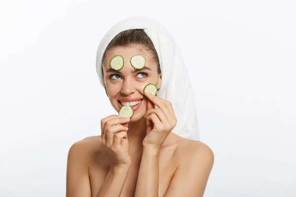 Donna con maschera facciale e fette di cetriolo tra le mani su sfondo bianco — Foto Stock