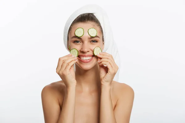 Mujer con máscara facial y rodajas de pepino en las manos sobre fondo blanco —  Fotos de Stock