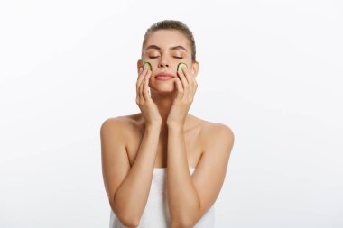 Havlu kafa ve dilim salatalık beyaz zemin üzerine izole el ile gülümseyen kadın Güzellik Portresi.