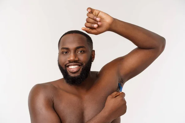 Primer plano de un hombre africano desnudo feliz afeitándose con navaja aislada sobre fondo gris —  Fotos de Stock