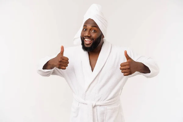 Pria kulit hitam mengenakan jubah mandi menunjukkan jempol dengan kejutan dan emosi bahagia. Terisolasi di atas latar belakang whtie. — Stok Foto