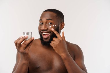 Afrikalı yakışıklı adam yüzüne krem sürüyor. Cilt bakımı kavramı