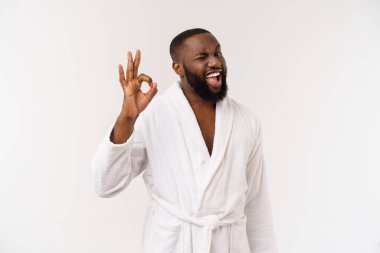 Bornoz genç Afrikalı adam ok parmak işareti gösteren cilt bakımı için hazırlar. İnsan duyguları konsepti