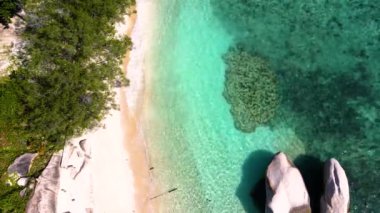 4K Hava Aracı deniz dalgaları, kaya ve kumu kuş bakışı görüyor. Deniz suyunun güzel dalgaları sahile gelir. Phuket Tayland tropik plajı.