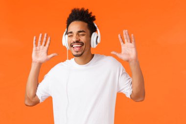 Harika bir ses kalitesi. Dertsiz, mutlu, gülümseyen, beyaz tişörtlü Afro-Amerikan adam favori müzikten zevk alırken şarkı söylüyor, kulaklıkla müzik dinliyor, gözlerini kapıyor ve gülümsüyor..