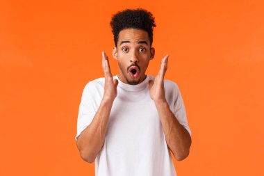 Etkilenmiş, afro-amerikan adam müthiş bir şey gördü, şaşırdı ve eğlendi, indirimleri kontrol etti, sezon indirimleri, çarpıcı performanslara katıldı, turuncu arka planda durdu..