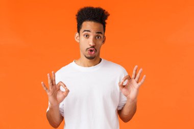 Eleman değerlendirmesi kötü film hakkında bilgi veriyor. Beyaz tişörtlü sevimli hippi, modern Afro-Amerikan erkek kişisel görüşlerini ifade ediyor, iyi bir jest, turuncu arka planda duruyor..