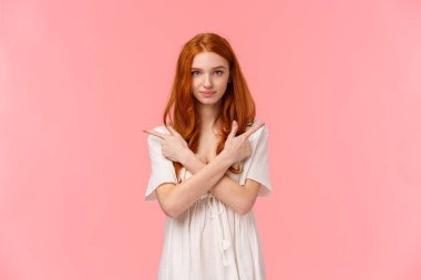 Seçim yapmak için senden yardım isteyen bir kız. Beyaz elbiseli çekici bir kızıl kadın, göğsünü yan gösteren çapraz eller, sol ve sağ ürünleri gösteren, ve gülümseyen kamerayı seçen..