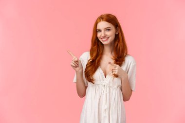 Bel yukarı portresi güzel Avrupalı, beyaz, moda elbiseli, üst sol köşesini gösteren kızıl saçlı kadın, davet gel ve çıkış promosyonu, tavsiye ver, pembe arka plan.