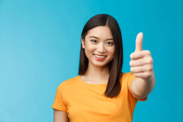 Close-up optimistic good-looking asian girl dark short haircut show thumb up, encourage friend congratulate good nice job, smiling delighted, give approval permission, stand blue background.