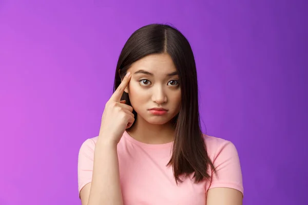 stock image Shocked asian girl scold friend unacceptable behaviour, pointing finger temple look confused and upset stare camera displeased weird actions, asking are you stupid, stand purple background.
