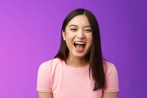 Close-up sincere carefree asian brunette laughing out loud, enjoy comedy movie, having fun, joking friends, stand entertained purple background amused, express positive emotions. Copy space