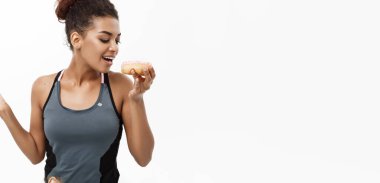 Sağlıklı ve diyet kavramı - güzel sportif Afrikalı-Amerikalı çörek ve yeşil elma arasında bir karar olun. Beyaz arka plan üzerinde izole