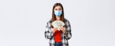 Para transferi, yatırım, covid-19 salgını ve ev konseptinden çalışma. Tıbbi maske takan ciddi görünümlü bir kadın serbest yazar ne kadar para kazandığını gösterir..