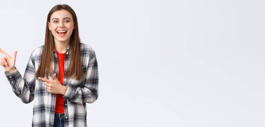 Yaşam tarzı, farklı duygular, boş zaman aktiviteleri konsepti. Hevesli, güzel bir genç kız gamsız gülüyor ve sol üst köşeyi işaret ediyor, yol gösteriyor, tanıtım öneriyor..