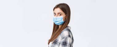 Coronavirus salgını, karantina, sosyal mesafeler ve duygu kavramı. Ciddi genç ve çekici bir kadının profil fotoğrafı. Tıp maskeli bir öğrenci. Kameraya dön..