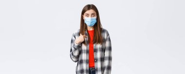 Coronavirus salgını, karantina, sosyal mesafeler ve duygu kavramı. Şok olmuş, tıbbi maskeli genç bir kız. Şaşırmış bir yüz ifadesi takınıyor..