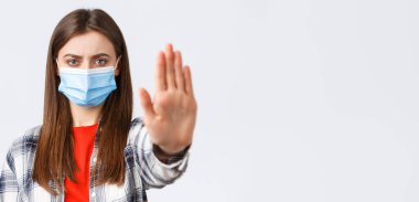 Coronavirus salgını, karantina, sosyal mesafeler ve duygu kavramı. Ciddi kararlı genç bayana yakın çekim yapmak, engelleme veya durdurma, kısıtlama veya uyarı amacıyla el uzatma.