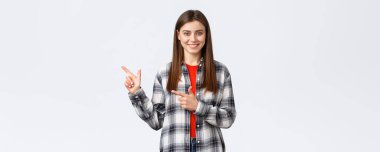 Yaşam tarzı, farklı duygular, boş zaman aktiviteleri konsepti. Tişörtlü, güzel sırıtan esmer kız, solu işaret ediyor, tanıtımın yolunu gösteriyor, tıklama linkini tavsiye ediyor ya da ürün satın alıyor..