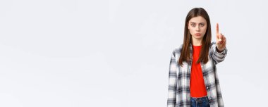 Yaşam tarzı, farklı duygular, boş zaman aktiviteleri konsepti. Ciddi şekilde endişeli genç bir kadın işaret parmağı gösteriyor, birini azarlıyor, ona durmasını, uyarmasını ya da yasaklamasını söylüyor, kötü karar vermesini engelliyor..