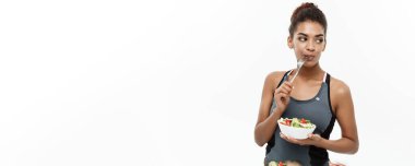 Sağlıklı ve Fitness kavramı - taze salata yemek diyet fitness giysili güzel Amerikan Afrika Bayan. Beyaz arka plan üzerinde izole