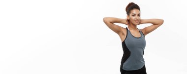 Sağlıklı ve Zindelik Konsepti - Beyaz stüdyo üzerinde spor kıyafetleriyle poz veren Afrikalı Amerikalı bir kızın portresi.