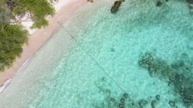 4K Hava Aracı deniz dalgaları, kaya ve kumu kuş bakışı görüyor. Deniz suyunun güzel dalgaları sahile gelir. Phuket Tayland tropik plajı