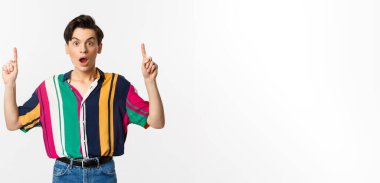 Şaşırmış cinsiyet değişkeni adam parmak kaldırıyor, şaşkın şaşkın bakıyor, müthiş bir promosyon teklifi sunuyor, beyaz arka planda duruyor..