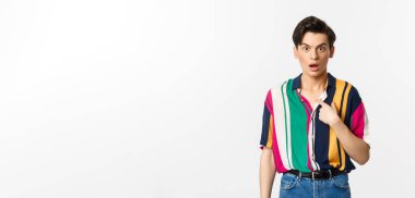 Kendini işaret eden, kafası karışmış, beyaz arka planda duran şaşırmış bir adam..