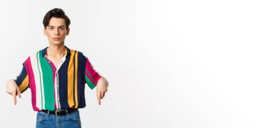 Genç, yakışıklı, eşcinsel bir adam. İlan veriyor ve ciddi görünüyor. Beyaz arka planda duruyor..