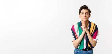 Yardım için yalvaran, kameraya bakıp yardım dilenen, tavsiye isteyen, beyaz arka planda duran umut dolu genç bir adam..