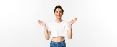 Lgbtq ve gurur konsepti. Mutlu ve tatmin olmuş genç gay adam topaç üstünde alkışlıyor gururla el çırpıyor, kameraya gülümsüyor, beyaz arka planda duruyor..