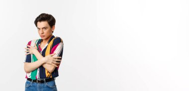 Ürkek eşcinsel adam görüntüsü kameraya karşı hoşnutsuz görünüyor, kendini savunuyor, beyaz arka planda duruyor..