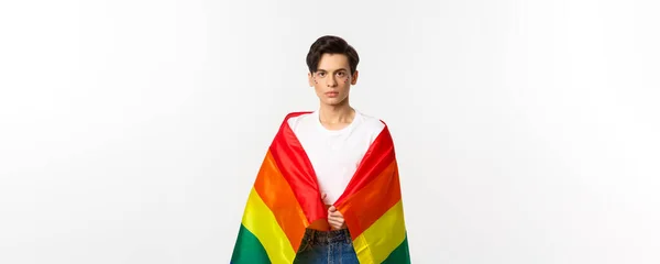 顔に輝きを放ち Lgbtqの虹の旗を身につけ 白い背景の上に立つ真剣な表情のジェンダー流体の人のイメージ — ストック写真