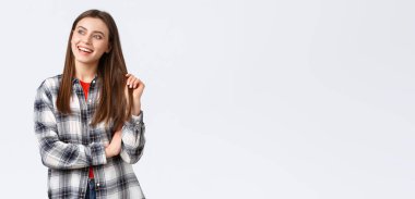 Yaşam tarzı, farklı duygular, boş zaman aktiviteleri konsepti. Hayalperest ve neşeli, mutlu, gülümseyen bir kadın. Düz tişörtlü bir bayan öğrenci. Sol üst köşeye bakıyor..