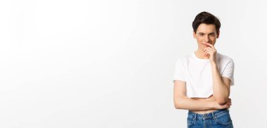 Lgbtq ve gurur konsepti. Tatmin olmuş genç eşcinsel bir adam, bir fikre sahip olmak ve kameraya bakarken gülümsemek, ekşi bluz, beyaz arka plan.