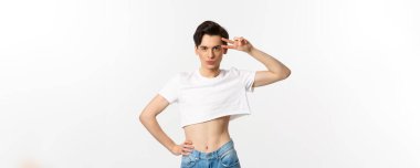 Güzel çift cinsiyetli adam beyaz arka planda duran barış işareti ve gülümseme gösteriyor..