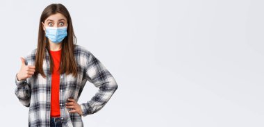 Coronavirus salgını, karantina, sosyal mesafeler ve duygu kavramı. Tıbbi maskeli, heyecanlı ve şaşırmış genç bir kadın çok iyi bir fikir duyuyor, onayını veriyor..