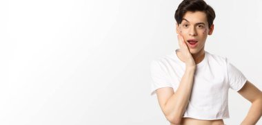 Millet, lgbtq ve güzellik konsepti. Yüzünde sim olan küstah ibne kameraya bakıyor, elleriyle yüzüne dokunuyor, beyaz arka planda duruyor..