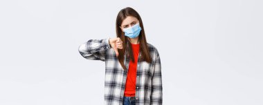 Coronavirus salgını, karantina, sosyal mesafeler ve duygu kavramı. Çok kötü bir fikir. Tıbbi maskeli, hoşnutsuz ve hoşnutsuz genç bir kadın onaylamıyor..