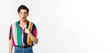 Kendini işaret eden, kafası karışmış, beyaz arka planda duran şaşırmış bir adam..