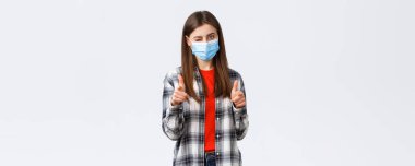 Coronavirus salgını, karantina, sosyal mesafeler ve duygu kavramı. Noktayı koyabilirsin. Tıbbi maskeli destekleyici genç ve çekici bir kadın kameraya bakıyor, göz kırpıyor ve tebrik ediyor..