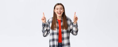 Yaşam tarzı, farklı duygular, boş zaman aktiviteleri konsepti. Hayalperest ve mutlu, kareli gömlekli genç bir kadın, rüyası gerçek oldu, tatil köyünü gösteriyor, parmaklarını kapalı gözlerle işaret ediyor..