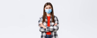 Coronavirus salgını, karantina, sosyal mesafeler ve duygu kavramı. Kendine güveni tam genç bir kadın. Tişörtlü. Tıbbi maske takıyor..