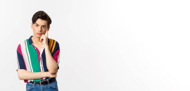 Çekici genç bir adamın beyaz arka planda durarak isteksiz ve rahatsız edici duygularla kameraya baktığı görüntüler..