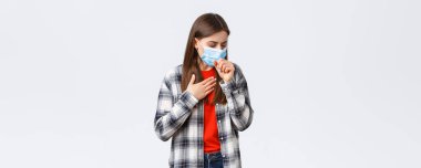 Coronavirus salgını, karantina, sosyal mesafeler ve duygu kavramı. Tıbbi maskeli bir kadın, öksürüyor, hasta hissediyor, akciğerlerine dokunuyor, kovid 19 belirtileri gösteriyor, hasta..