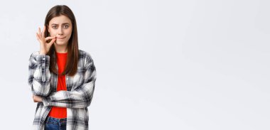 Yaşam tarzı, farklı duygular, boş zaman aktiviteleri konsepti. Ciddi görünümlü genç bir kadın söz verir ağzını kapalı tutar, mühürlü dudaklar yapar, fermuarını çeker ve kameraya bakar..